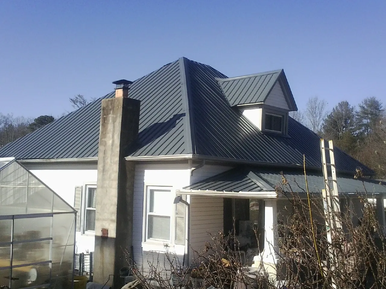 Dark blue standing seam metal roof on a white farmhouse with dormer — Slate & Tile Roof Repair by Roofing Brothers in Excelsior
