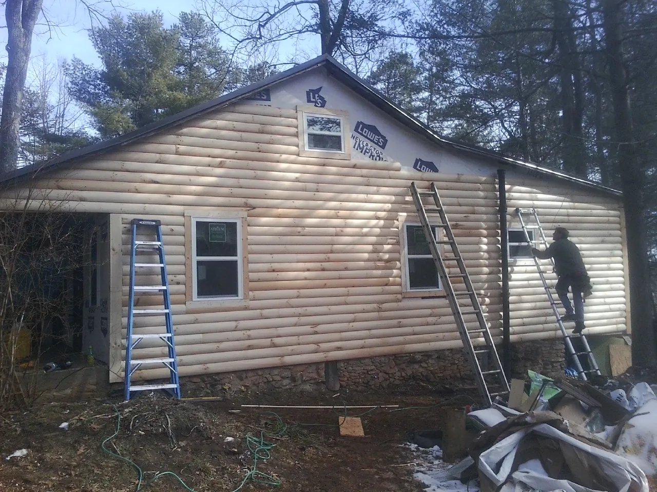 Ladders set against fresh log siding during an exterior remodel in Excelsior