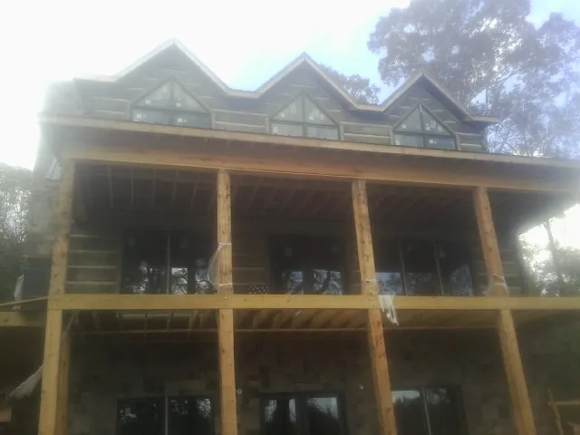 Dormers and porch framing on a large log home under construction — Roof Coating work by our crew in Excelsior