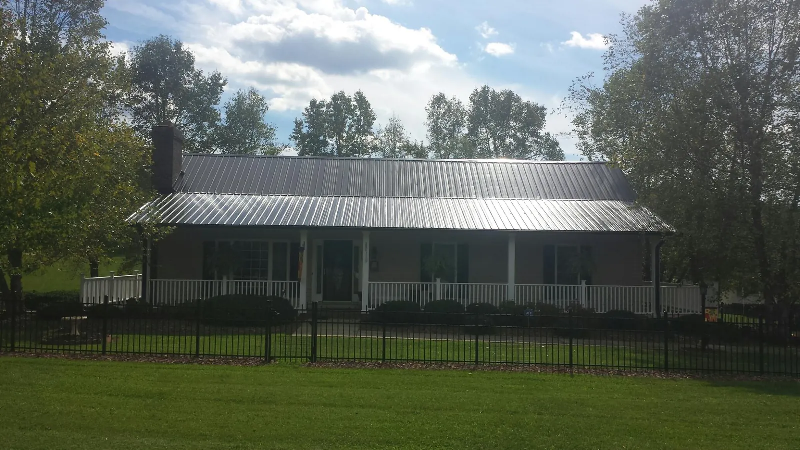 Gray metal roof on a brick ranch with a full width front porch — Gutter Guard Installation work by our crew in Excelsior