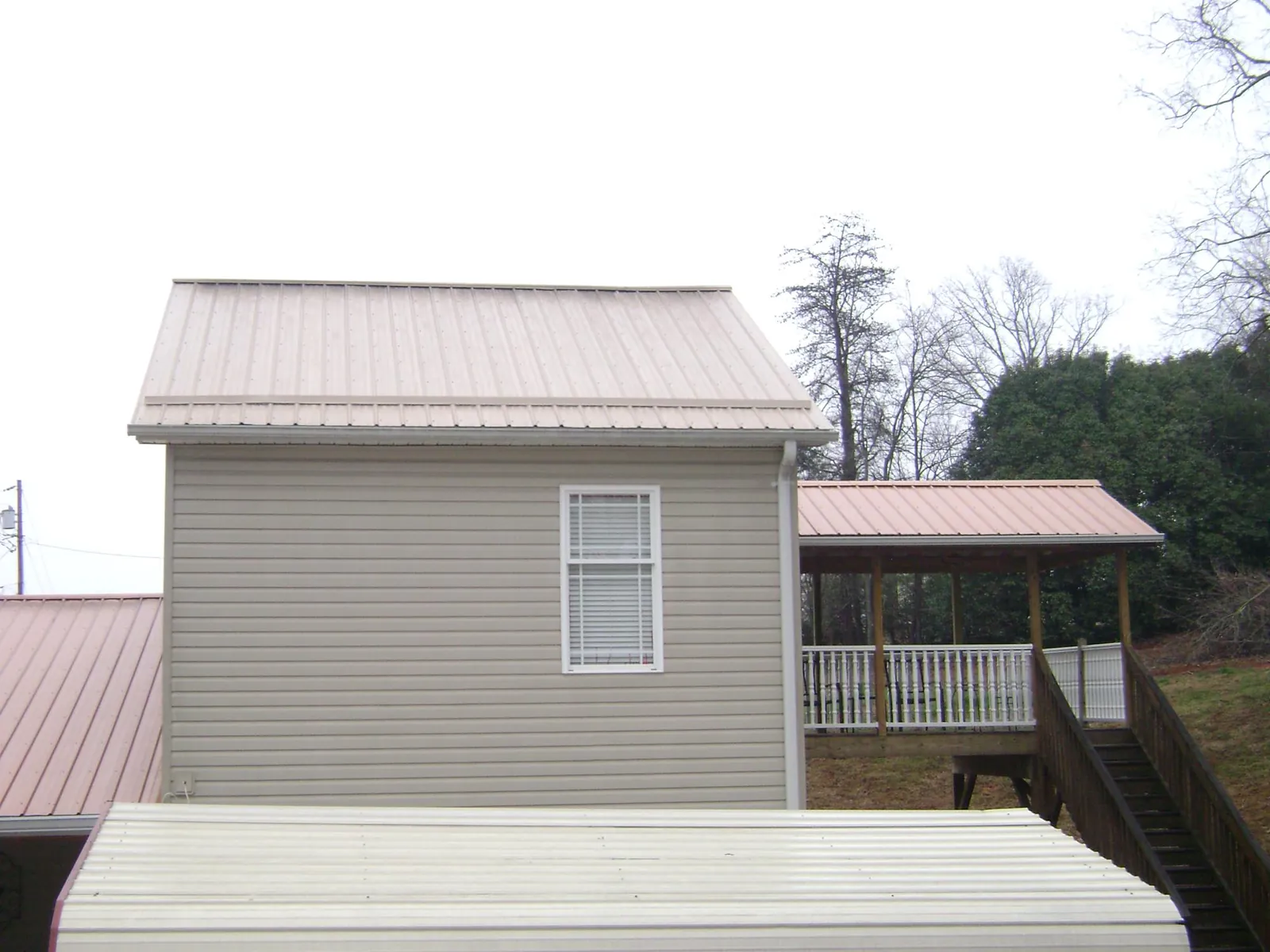 Tan metal roofs on a two story addition and attached porch, from a Roof Replacement job in Excelsior