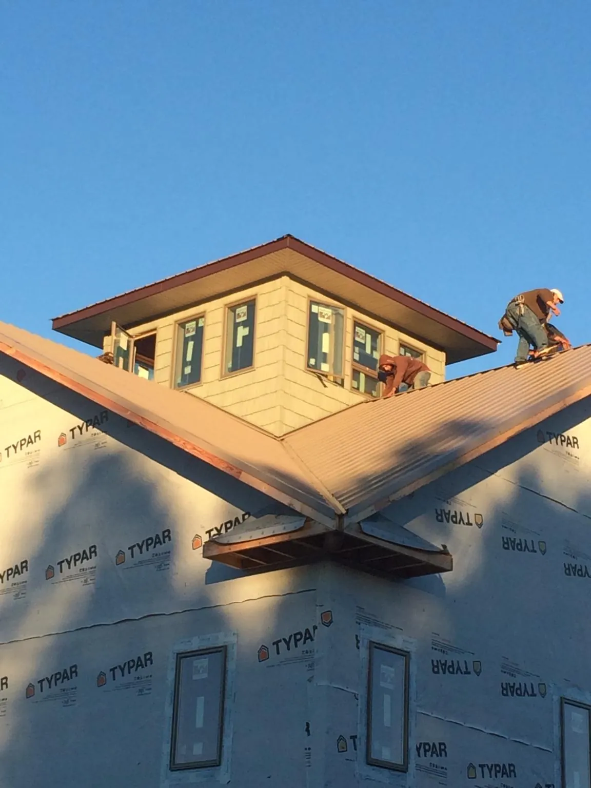 Roofers working around a rooftop cupola on a new metal roof at sunset — Roof Waterproofing in Excelsior by Roofing Brothers